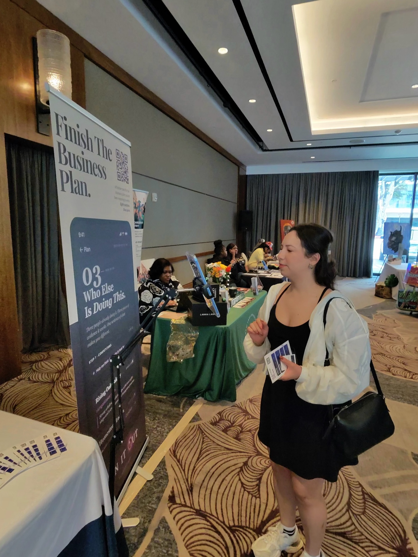 Attendee reading the Plan It Out banner at the Chronicle House booth across the aisle.